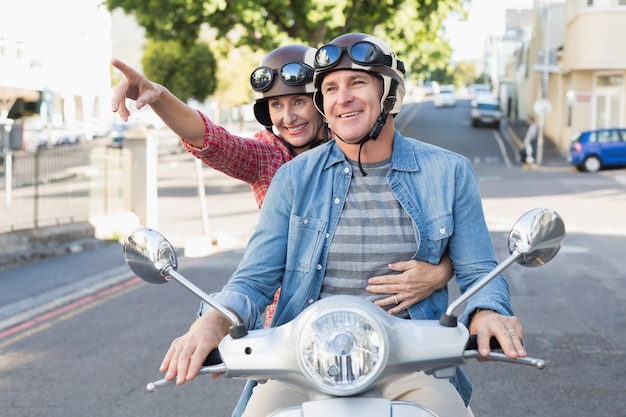 Foto coppie mature felici che guidano un motorino nella città