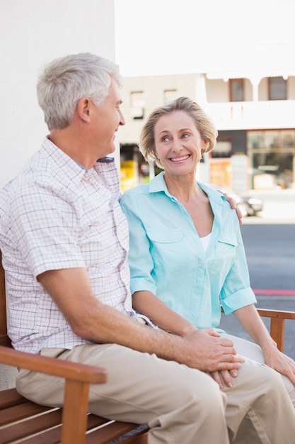 Happy mature couple sitting on bench in the city