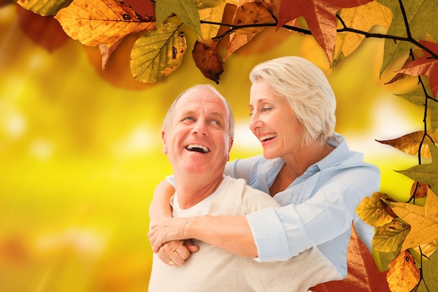 Happy mature couple smiling at each other against golden leaves