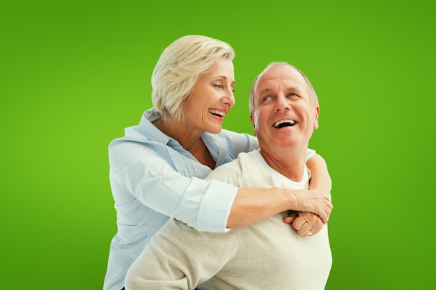 Happy mature couple smiling at each other against green vignette
