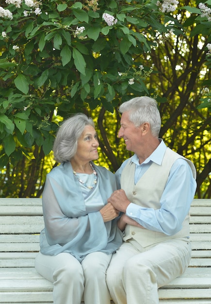 Счастливая зрелая пара в весенний день, сидя на скамейке