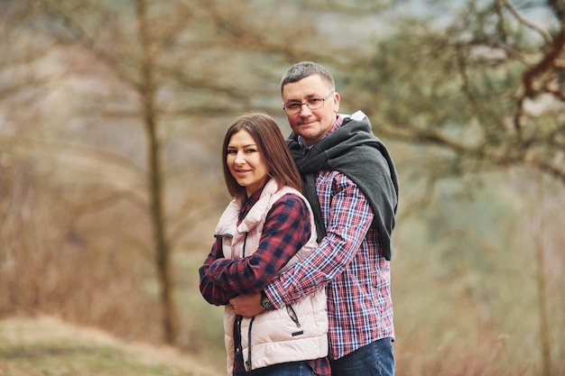 Happy mature couple standing and embracing each other outdoors in forest