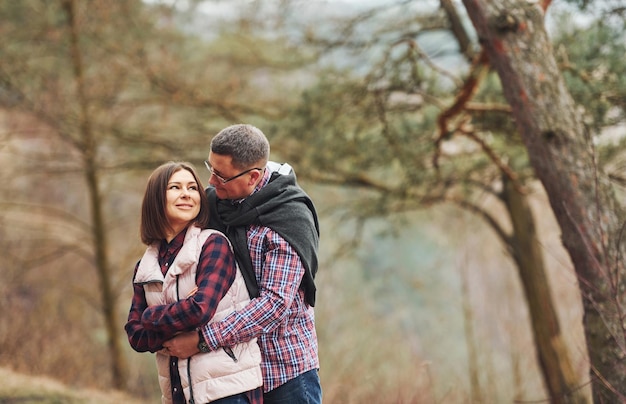 Happy mature couple standing and embracing each other outdoors in forest