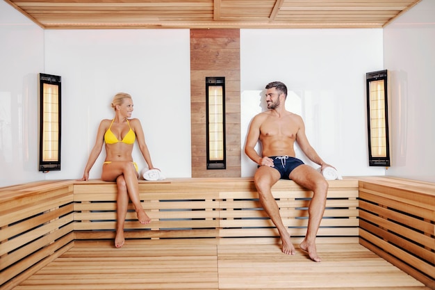 A happy mature couple in swimwear sitting in a sauna at a spa center and sharing moments