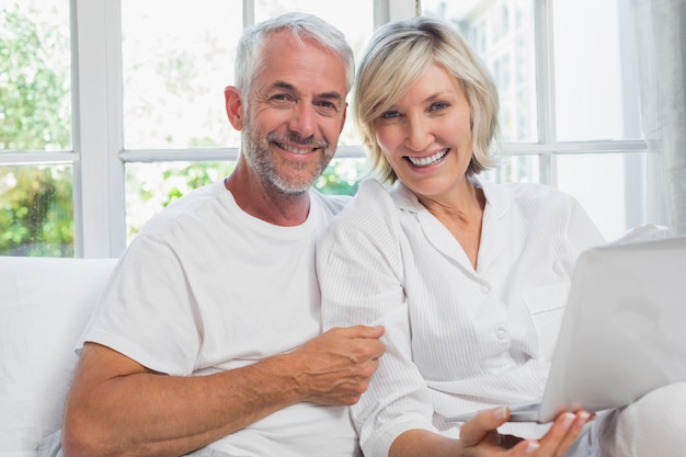 Happy mature couple using laptop in bed