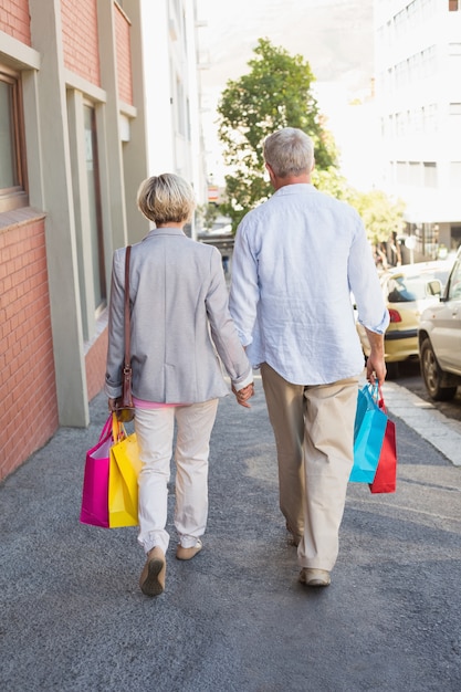 Happy mature couple walking with their shopping purchases