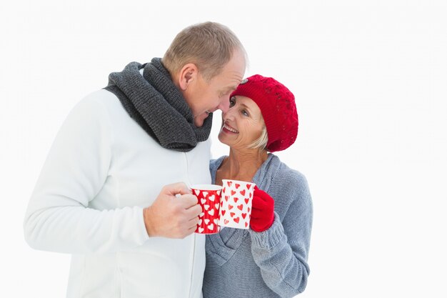 Le coppie mature felici nell'inverno copre le tazze della holding