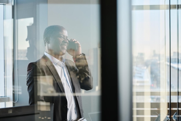 Happy mature director of business company talking on smartphone