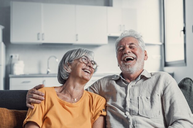 Photo happy mature husband and wife sit rest on couch at home hugging and cuddling show care affection smiling senior loving couple relax on sofa have fun enjoy tender romantic family weekend togetherxa