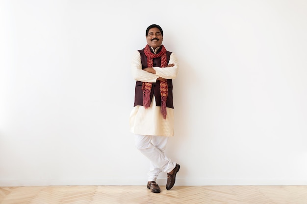 Happy mature indian man in national clothes posing on white