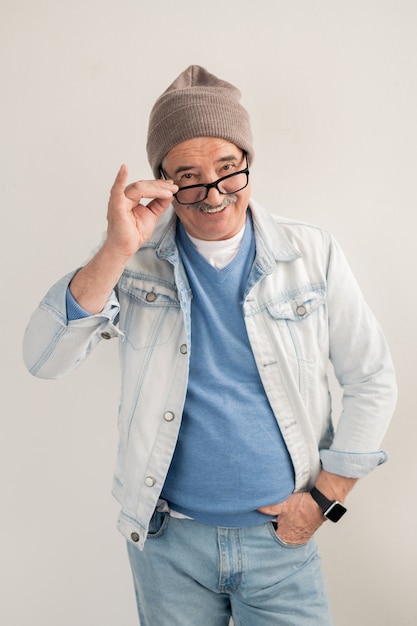 Happy mature man in casualwear standing and looking at you through eyeglasses