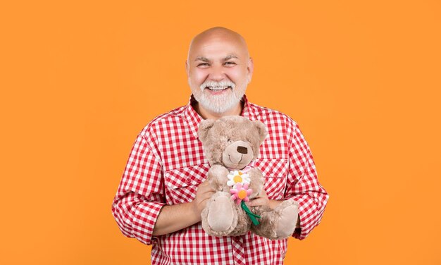 Photo happy mature man in checkered shirt with toy on yellow background