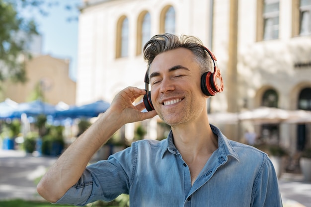 Happy mature man listening to music on headphones