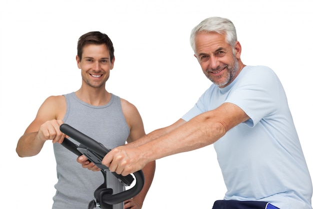 Happy mature man on stationary bike with trainer