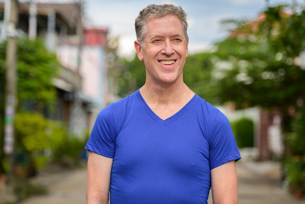 Photo happy mature man thinking in the streets outdoors