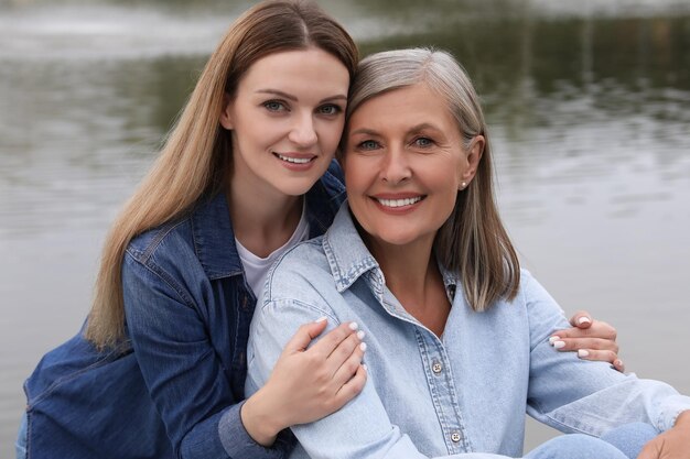 Photo happy mature mother and her daughter near pond