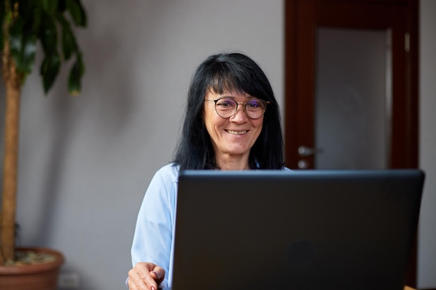 Felice donna anziana matura chiamata in conferenza nella riunione di chat video sul laptop