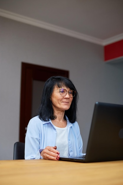 Felice donna anziana matura chiamata in conferenza nella riunione di chat video sul laptop