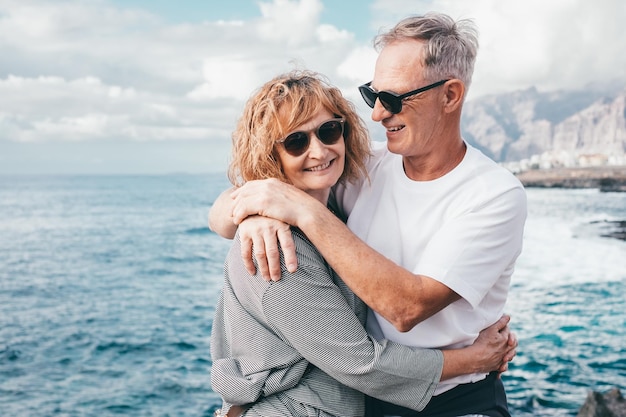 Happy mature and romantic senior couple embrace each other on the seashore expressing love