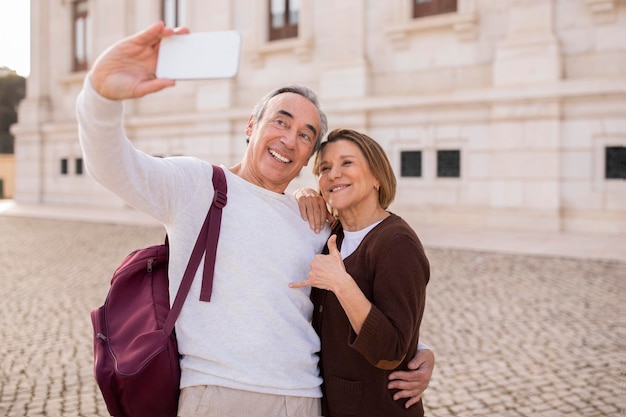 Happy mature travelers spouses snapping selfies via smartphone in lisbon