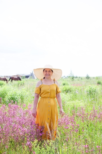 Happy mature woman in a hat and sundress in summer outdoors