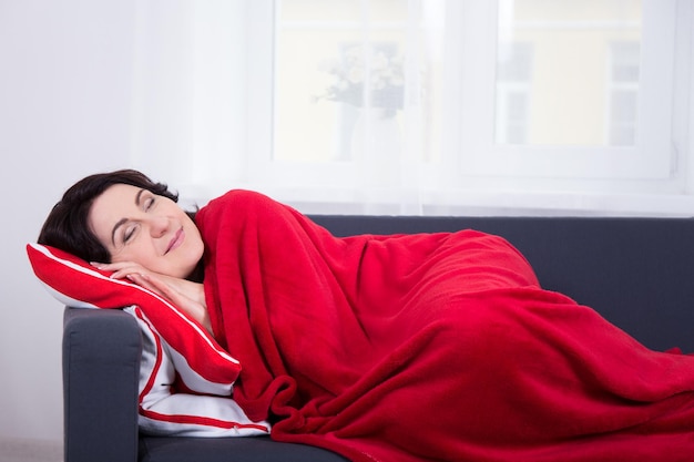 Happy mature woman sleeping on sofa at home