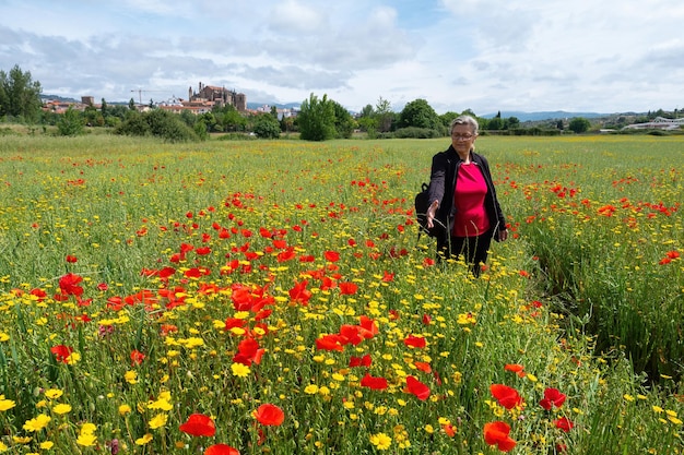 Happy mature woman traveller holding bouquet of red poppy flowers