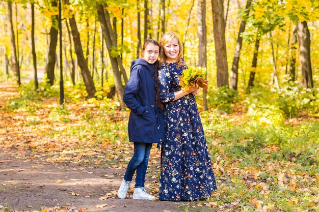 Happy mature woman with adult daughter in autumn park