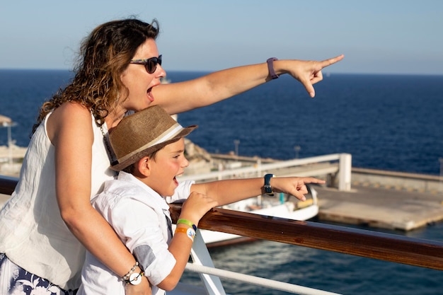 Photo happy mature woman with son on boat pointing towards sea