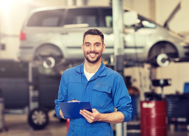 happy mechanic man with clipboard at car workshop