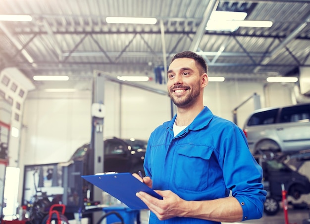 Foto uomo meccanico felice con clipboard in un'officina automobilistica