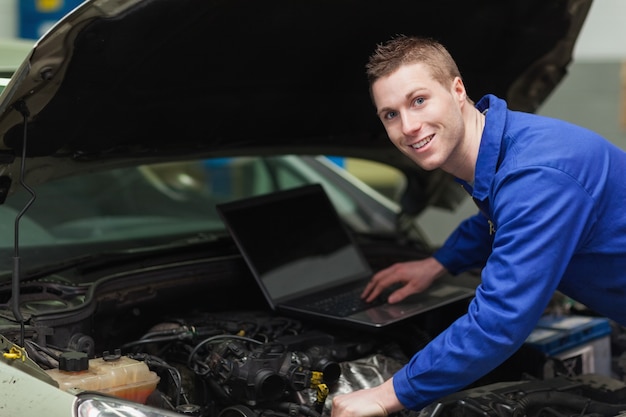 Photo happy mechanic using laptop