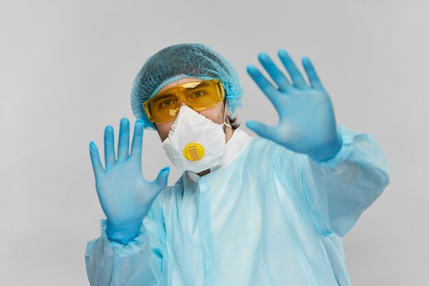 Happy medical scientist in protactive suit distancing from camera with arms in blue disposable gloves