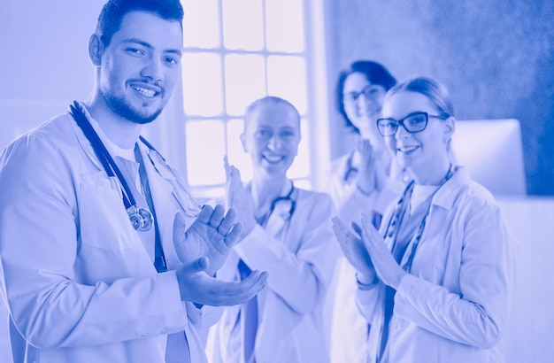 Happy medical team comprising male and female doctors smiling broadly and giving a thumbs up of success and hope