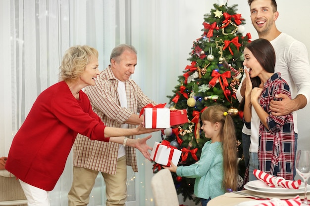 Happy members of family giving Christmas presents to each other