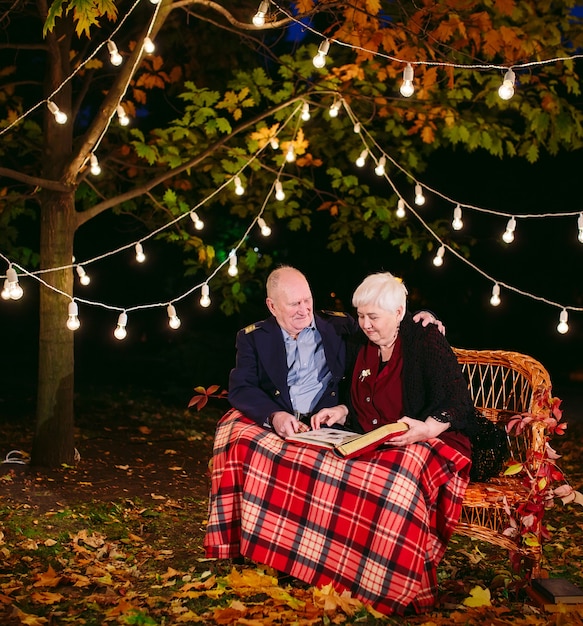 Happy memories. Happy senior couple sitting on sofa watching album with photos.