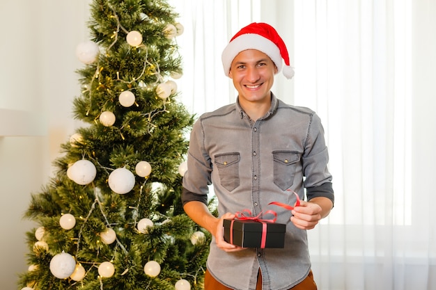 Happy mid adult man near Christmas tree at home