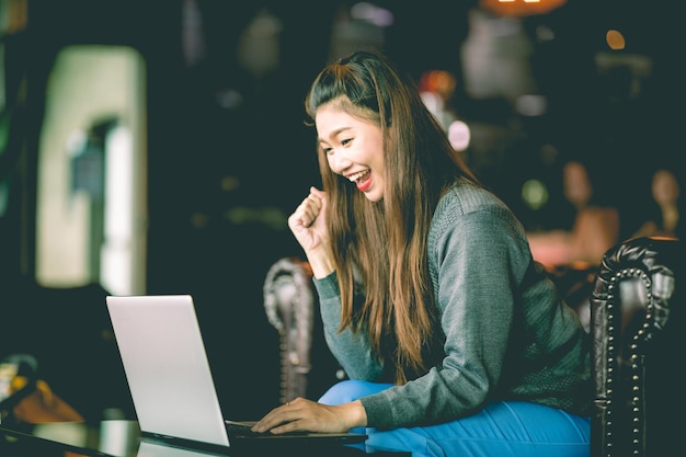 happy mid adult woman using laptop in cafe