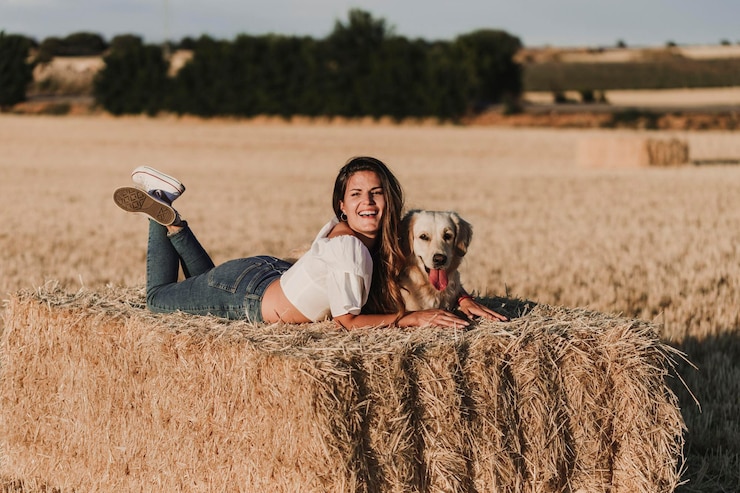 Photo happy mid adult woman with dog lying on hay at agricultural field