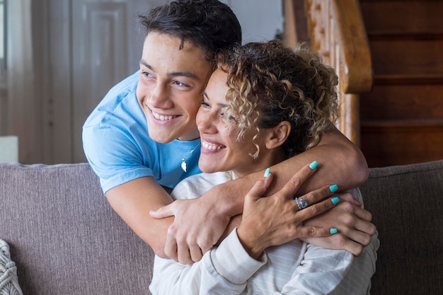 Happy middle age mother spend time with teenager son relatives people hugging at home adult