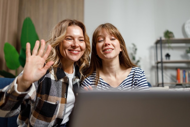 Happy middle age woman and adult daughter waving hand