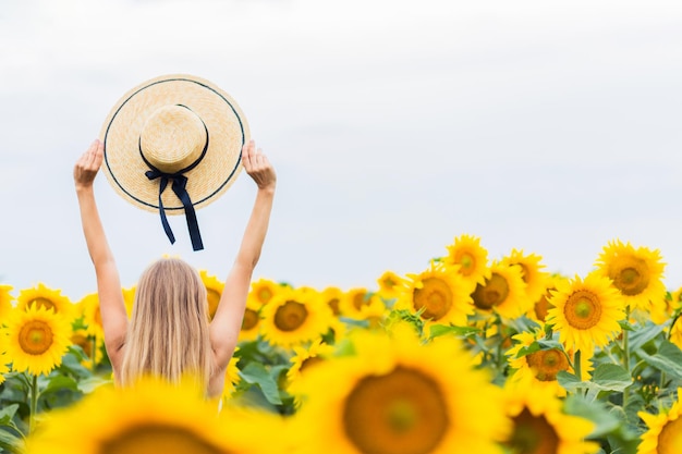 Happy middle age woman walking in blooming sunflower field