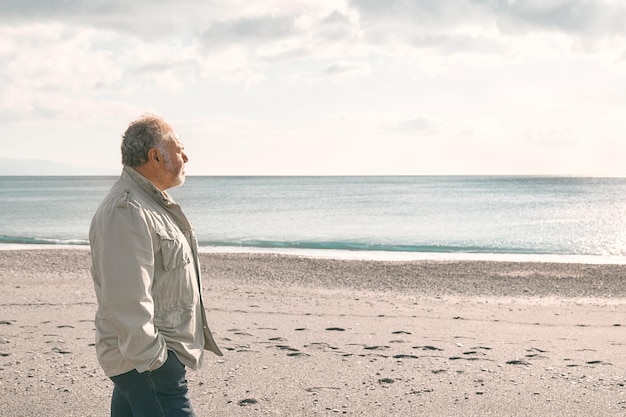 Photo happy middle-aged bearded man walking along deserted winter beach