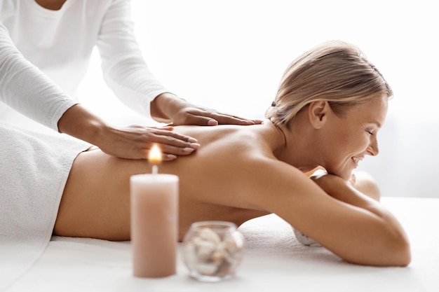 Happy middle aged female enjoying aromatherapy massage in modern beauty center