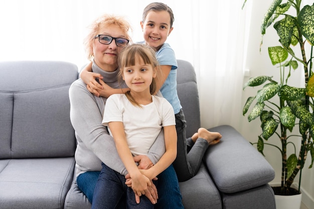 Happy middle-aged mature grandma and little preschooler two granddaughters having fun playing at home.