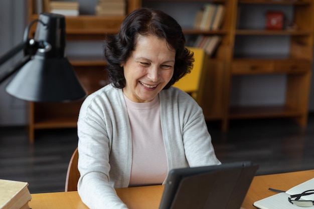 Happy middle aged senior woman holding tablet talk on video call with friends family laughing mature