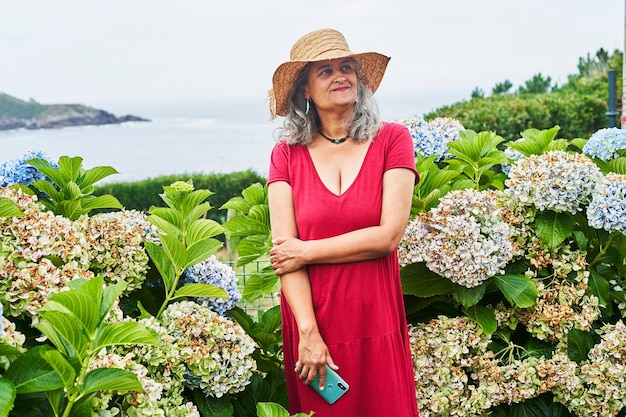 Happy middle-aged woman in red dress near the sea