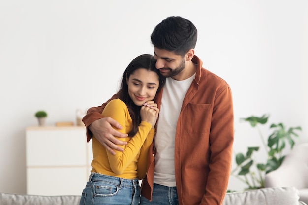 Happy middle eastern couple embracing standing at home