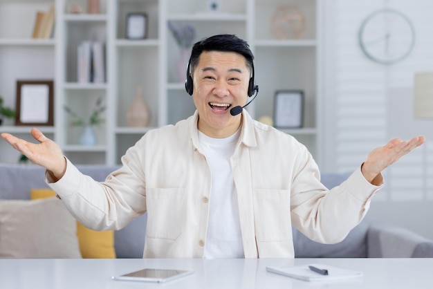 Happy middleaged asian man wearing headset smiling and gesturing while providing customer service