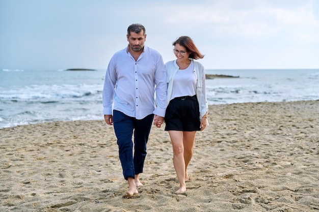 浜辺を一緒に歩く幸せな中年夫婦